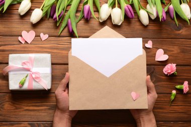 Zarflı erkek eller, boş kart ve tahta arka planda hediye kutusu. Uluslararası Kadınlar Günü kutlamaları