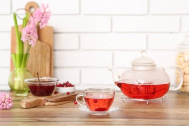 Çaydanlık ve bir fincan yaban mersini çayı. Mutfaktaki masanın üstünde sümbül var.