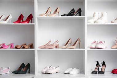 Farklı kadın ayakkabılarıyla beyaz raf ünitesi.