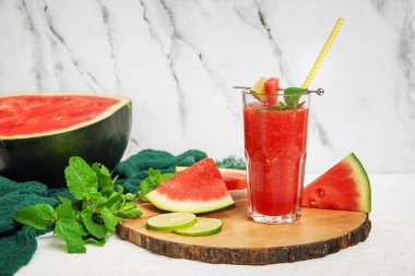 Bir bardak taze karpuz suyu, beyaz arka planda limon ve nane.