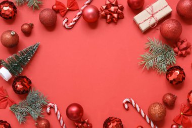 Kırmızı arkaplanda Noel topları ve köknar dallarından yapılmış çerçeve