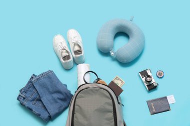 Seyahat eşyaları, elbiseler ve ayakkabılar mavi arka planda.