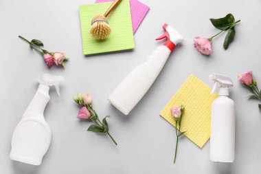 Aletlerle temizlik malzemeleri ve gri arka planda Eustoma çiçekleri