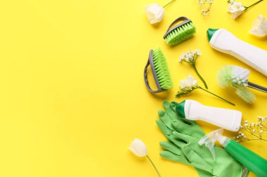 Aletlerle temizlik malzemeleri ve sarı arka planda güzel çiçekler.