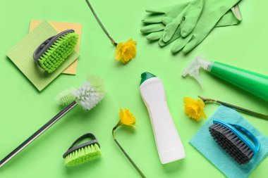 Aletlerle temizlik malzemeleri ve yeşil arka planda nergis çiçekleri