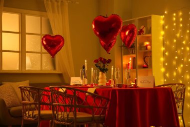 Akşamları yanan mumlar, balonlar ve güllerle dolu güzel bir masa. Sevgililer Günü kutlaması