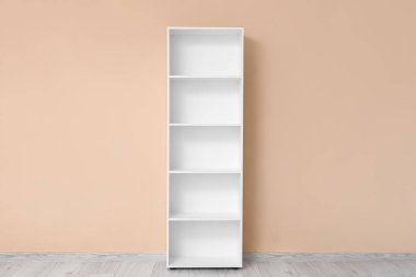 Bej duvarın yanında boş beyaz raf ünitesi