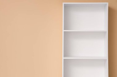 Bej arkaplanda boş beyaz raf ünitesi, yakın plan