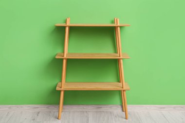 Yeşil duvarın yanındaki boş ahşap raf ünitesi.
