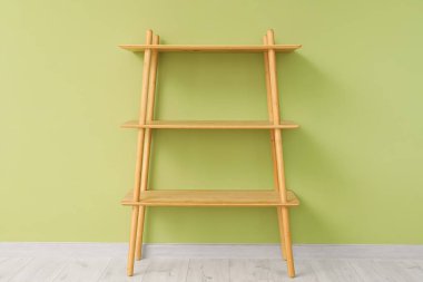 Yeşil duvarın yanındaki boş ahşap raf ünitesi.
