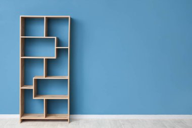 Mavi duvarın yanındaki boş ahşap raf ünitesi.