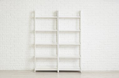 Beyaz tuğla duvarın yanındaki boş raf ünitesi
