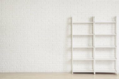 Beyaz tuğla duvarın yanındaki boş raf ünitesi