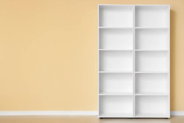 Bej duvarın yanında boş beyaz raf ünitesi