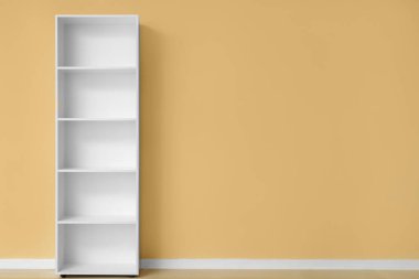 Bej duvarın yanında boş beyaz raf ünitesi