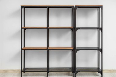 Beyaz duvarın yanında boş siyah raf ünitesi