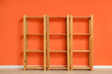 Turuncu duvarın yanındaki boş ahşap raf ünitesi.