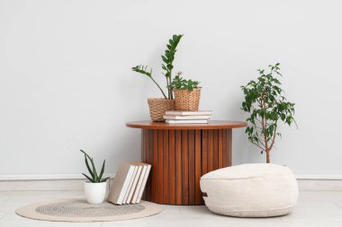 Masa, puf ve yeşil bitkilerle aydınlatma odasının içinde.