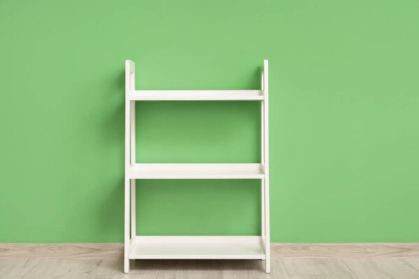 Empty white shelving unit near green wall