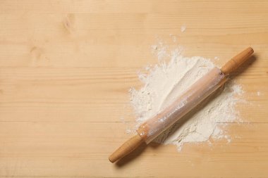 Ahşap zemin üzerinde un serpiştirilmiş merdane.