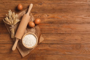 Bir kase un, çivili buğday ve ahşap zemin üzerinde yumurtalar.