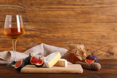 Lezzetli Camembert peyniri ve ahşap arka planda taze incir parçaları.