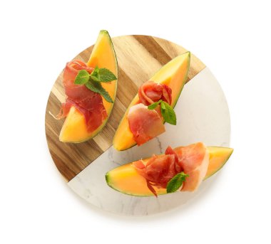 Lezzetli prosciutto ve beyaz arka planda nane yapraklı taze kavun parçaları.