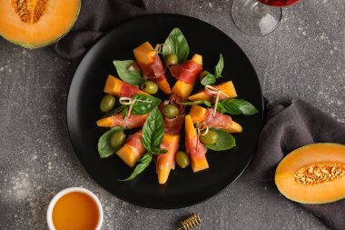 Lezzetli prosciutto, zeytin ve fesleğen yapraklı taze kavun parçaları.