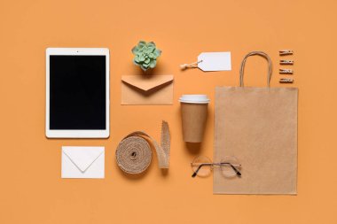 Tablet bilgisayarlı kompozisyon, bir fincan kahve ve turuncu arka planda teslimat kağıdı.