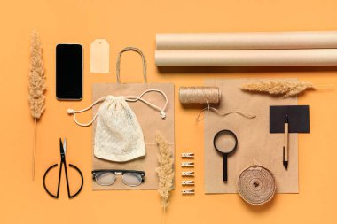 Portakal rengi arka planda cep telefonu, el işi kağıdı, sicim ve teslimat çantası olan kompozisyon