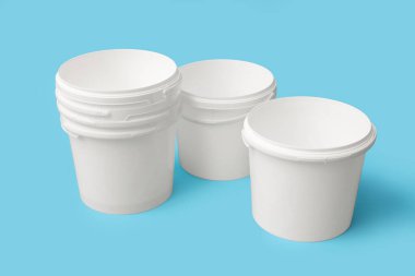 Mavi arka planda beyaz plastik boya kovaları