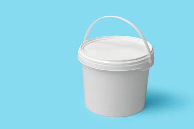 Mavi arka planda plastik boya kovası