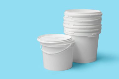 Mavi arka planda beyaz plastik boya kovaları