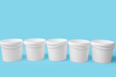 Birçok açık plastik boya kovaları mavi arka planda