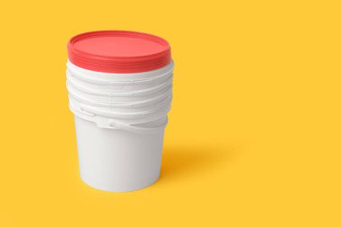 Sarı arka planda plastik boya kovaları