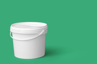 Yeşil arka planda plastik boya kovası