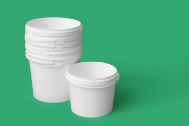 Yeşil arka planda beyaz plastik boya kovaları