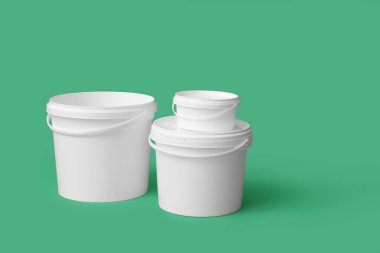 Yeşil arka planda plastik boya kovaları