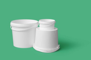 Yeşil arka planda plastik boya kovaları