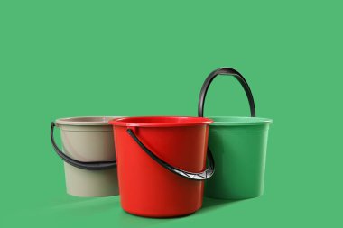 Yeşil arkaplanda plastik kovalar