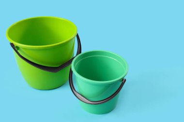 Mavi arkaplanda yeşil plastik kovalar