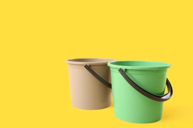 Sarı arkaplanda plastik kovalar