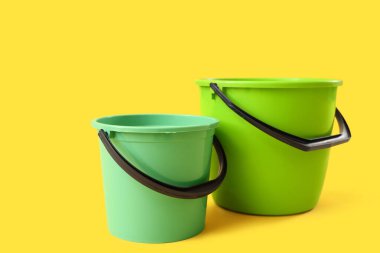 Sarı arkaplanda yeşil plastik kovalar