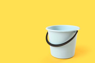 Sarı arka planda beyaz plastik kova