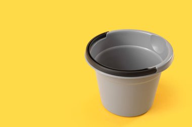 Sarı arka planda gri plastik kova