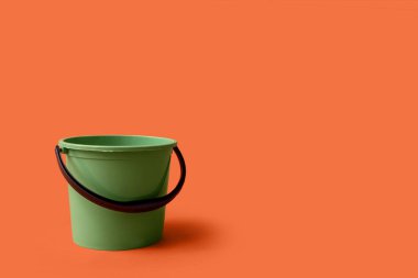 Turuncu arka planda yeşil plastik kova