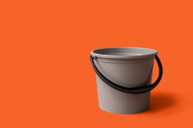 Turuncu arka planda gri plastik kova