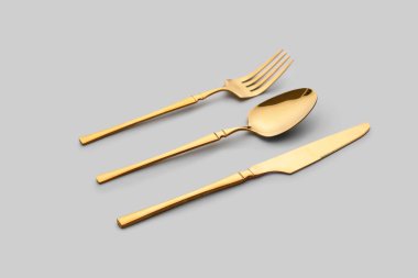 Gri arkaplanda şık altın çatal bıçak takımı