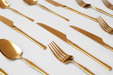 Gri arka planda şık altın çatal bıçak takımı, yakın plan.
