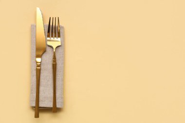 Sarı arka planda bıçak ve peçeteli altın çatal